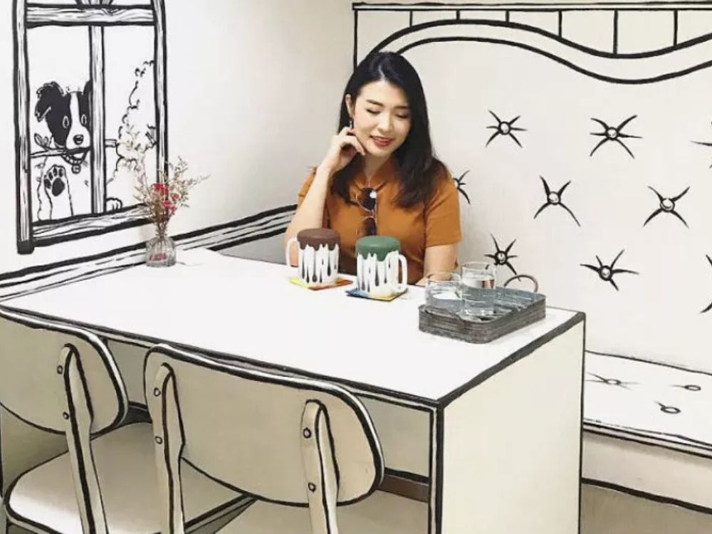 Imagem de uma mulher tomado café em uma cafeteria temática inspirada em desenho animado na Coreia do Sul